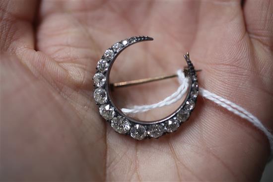 An Edwardian silver, gold and graduated diamond set crescent brooch, 27mm.